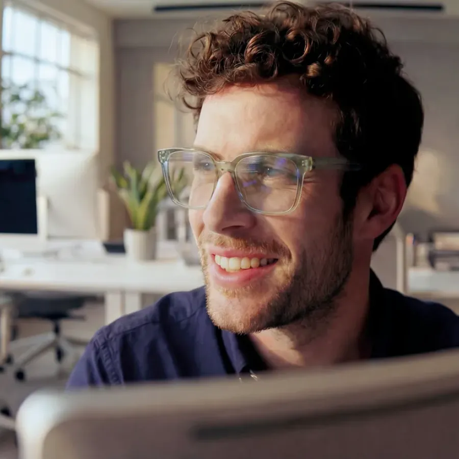 Arbeitsplatzbrille aktivoptik - Mann mit Lächeln und Brille mit Officegläsern in einem Büro mit Pflanzen