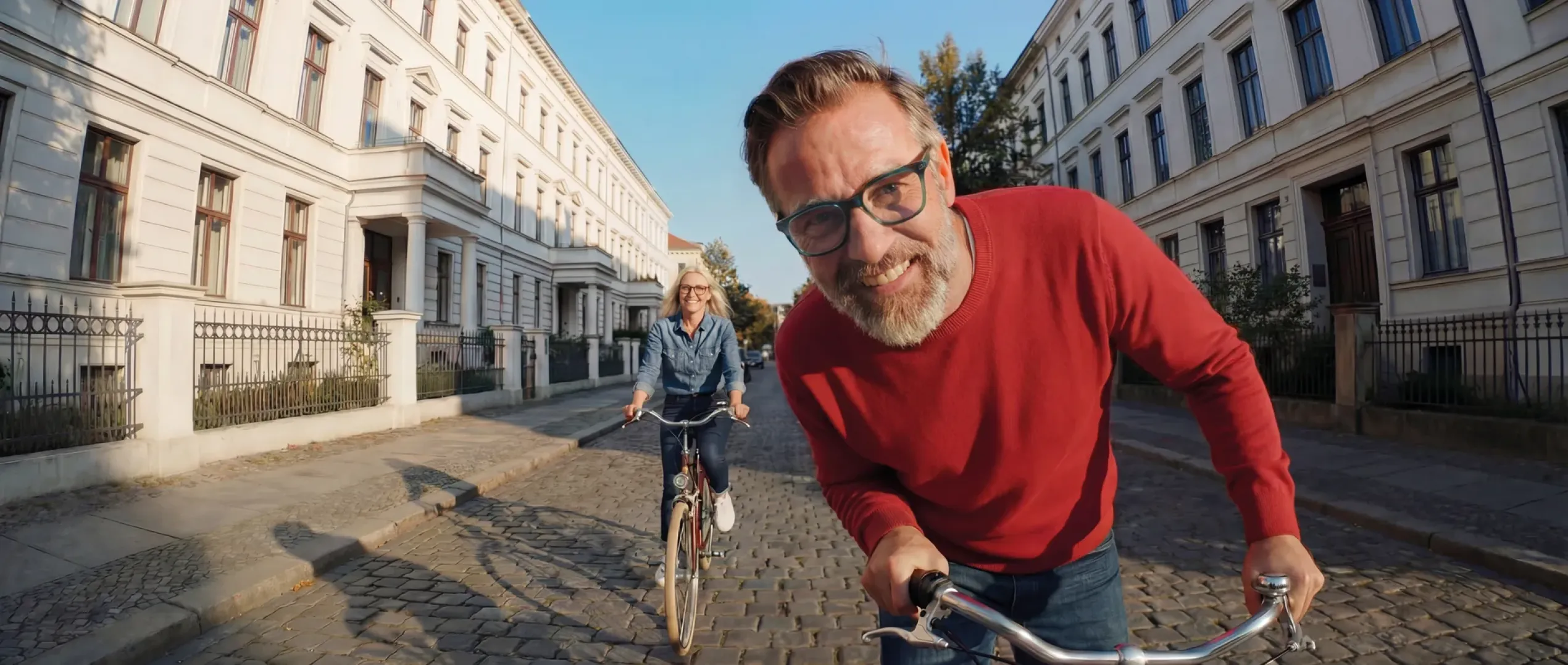Banner aktivoptik - Mann und Frau mit Brille fahren in einer Stadt Fahrrad, Nahaufnahme des Mannes, die Frau ist im Hintergrund