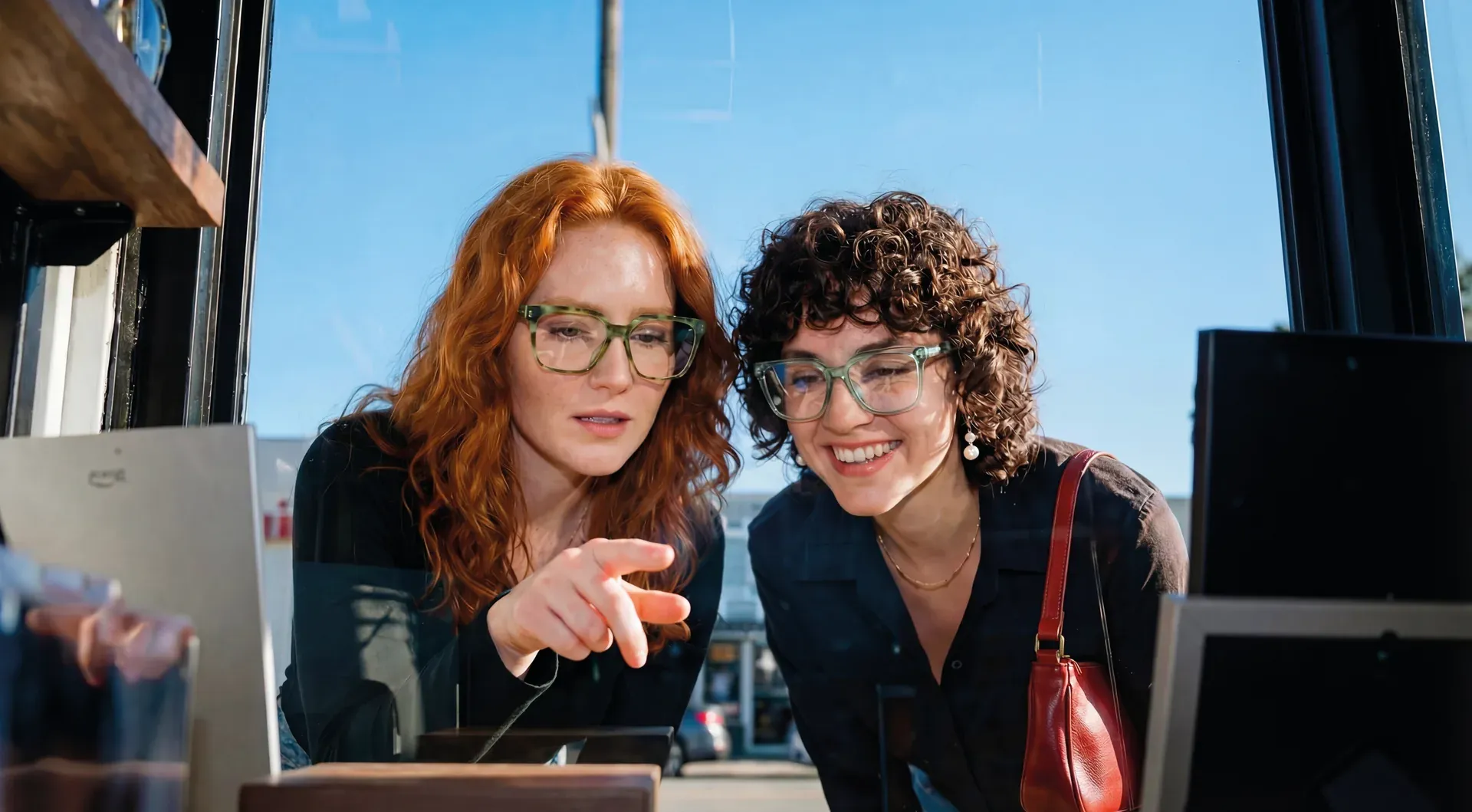 Rahmenformen aktivoptik - Zwei Frauen mit Brille stehen vor einem Schaufenster und eine zeigt mit dem Fingre auf eine Brillenfassung